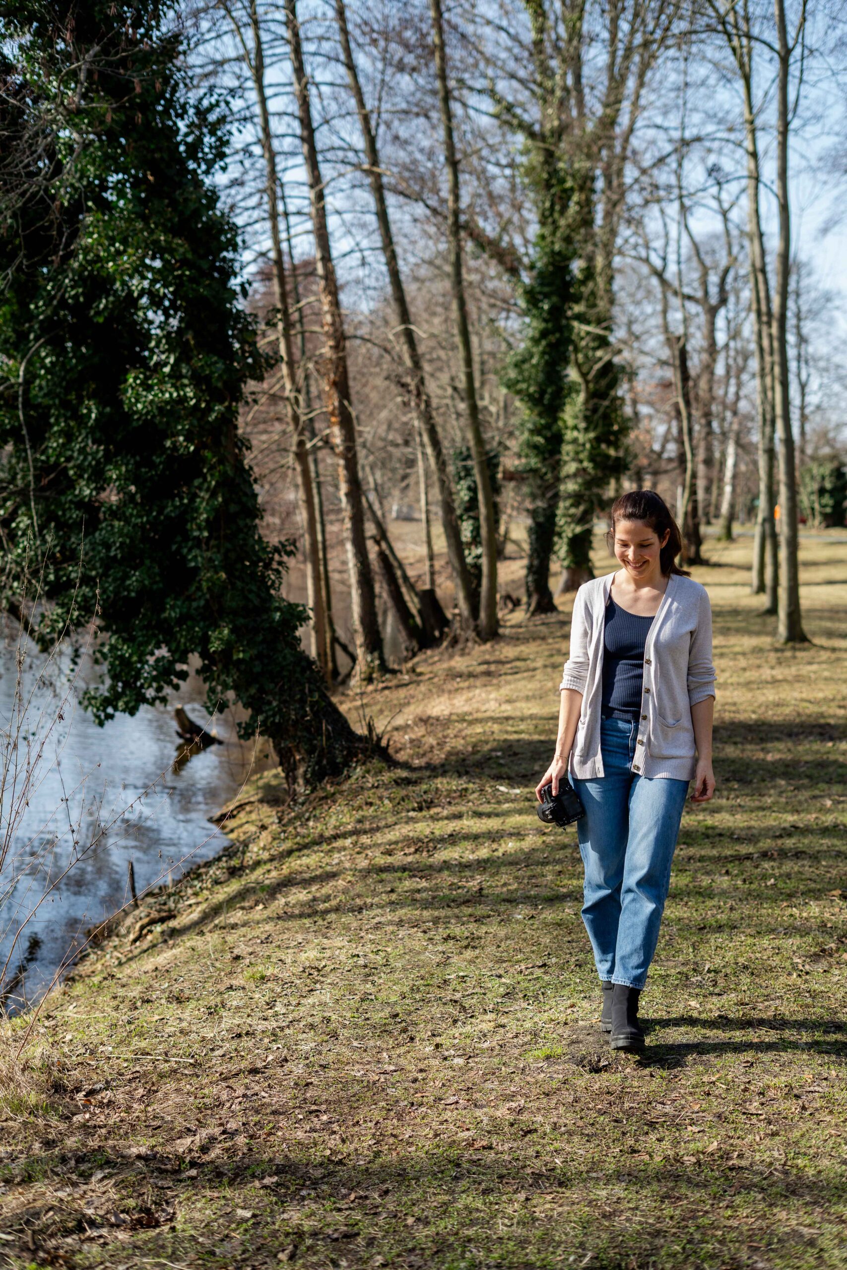 Fotografin läuft mit der Kamera in der Hand an einem Fluss entlang