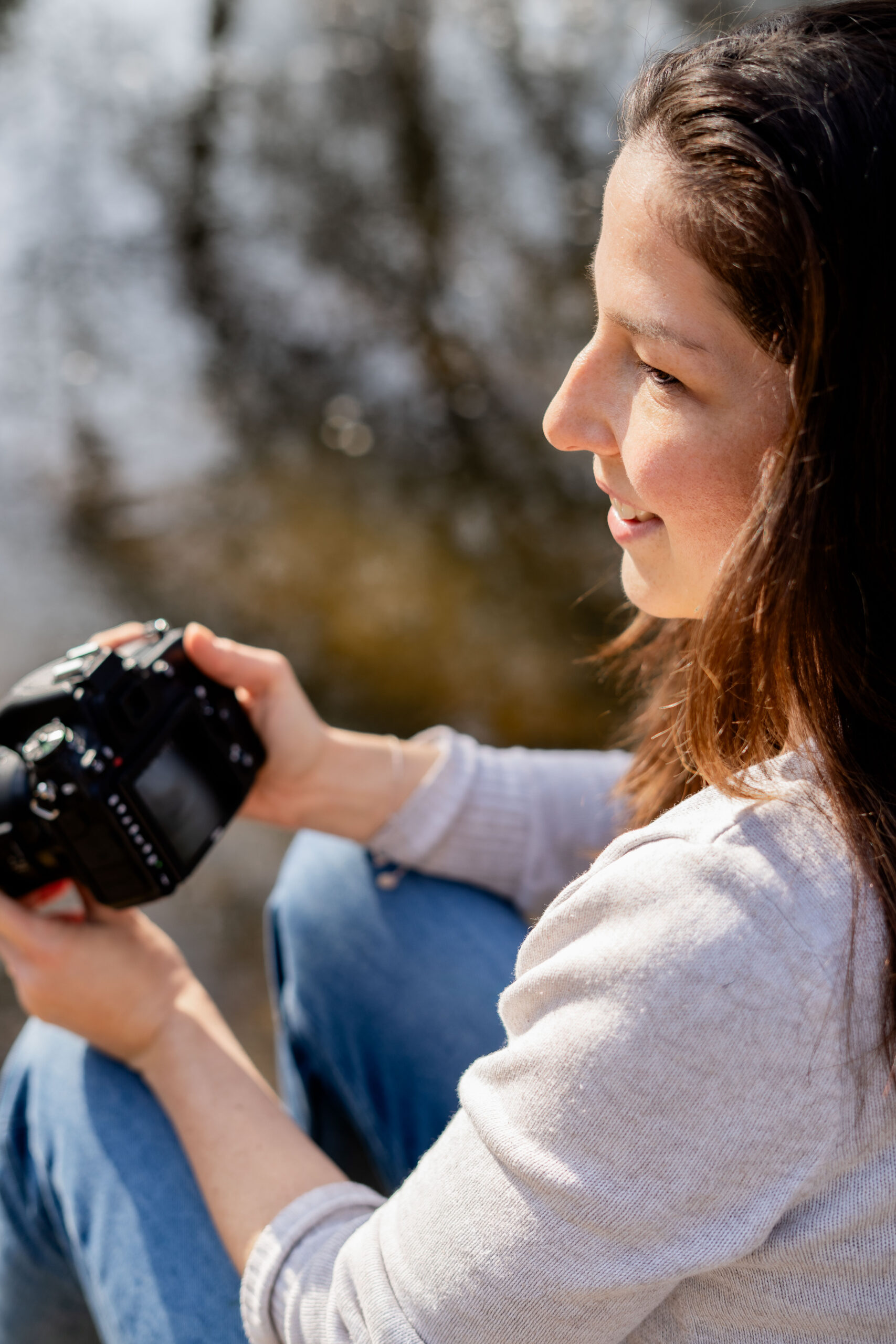 Nahaufnahme von der Fotografin im Profil während sie Fotos auf der Kamera sichtet