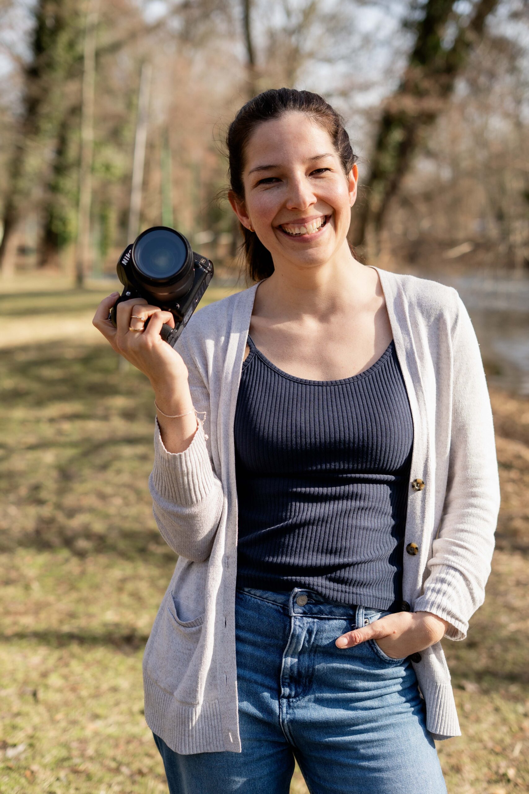 Familienfotografin mit Kamera in der Hand lächelt in die Kamera